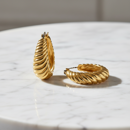 Gold hoop earrings on a marble surface