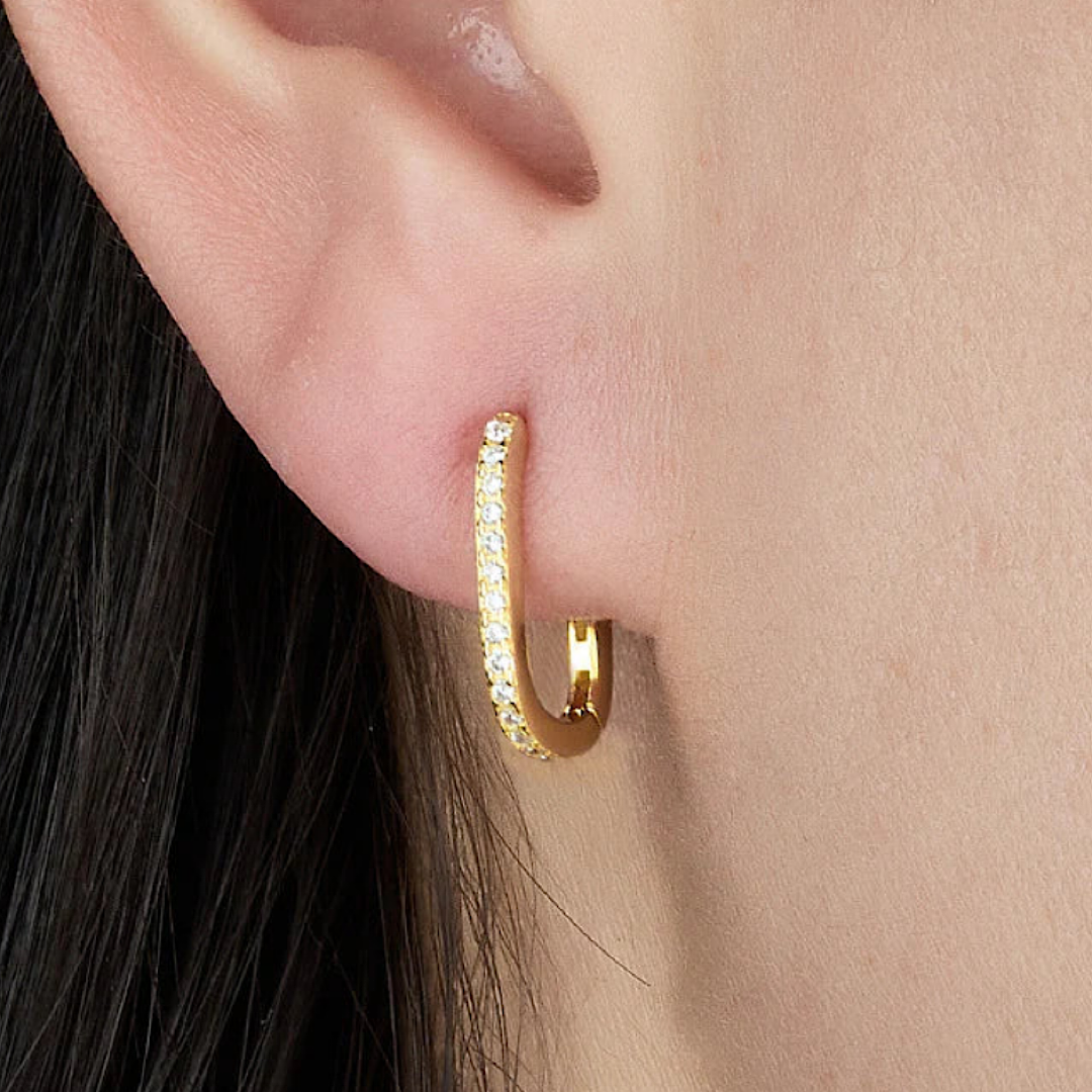 Gold hoop earring worn by a person with black hair.