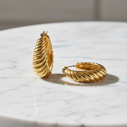 Gold hoop earrings on a marble surface