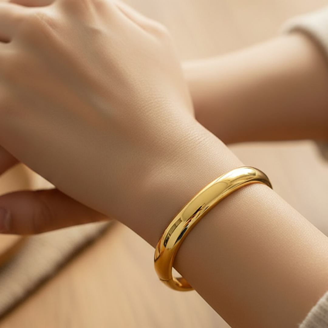 Gold bracelet on a wrist with a neutral background