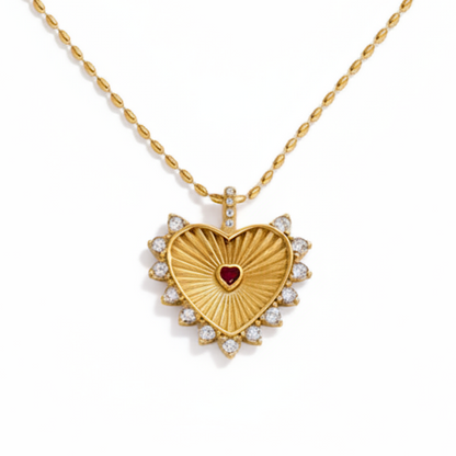Gold heart-shaped necklace with a red gemstone center on a white background
