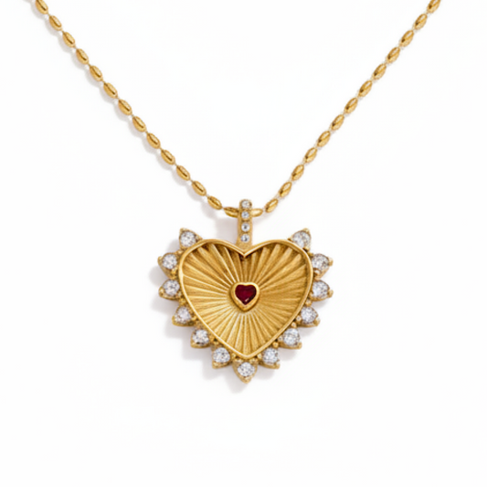 Gold heart-shaped necklace with a red gemstone center on a white background