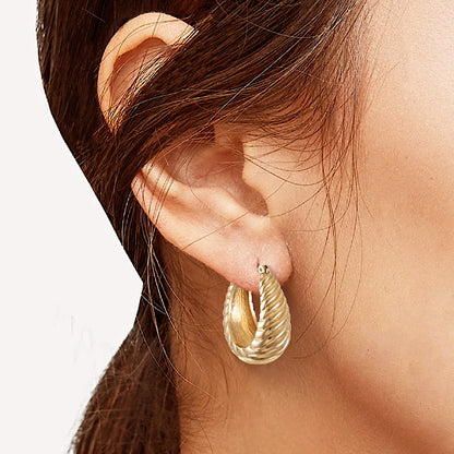 Gold hoop earring worn by a person with a neutral background