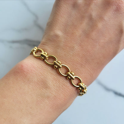 Gold chain bracelet on a wrist with a light background