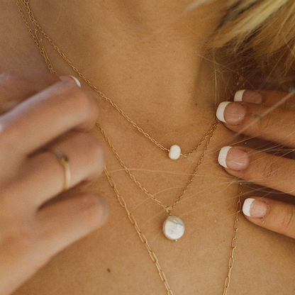 Gold chain necklace with small round stones worn around the neck